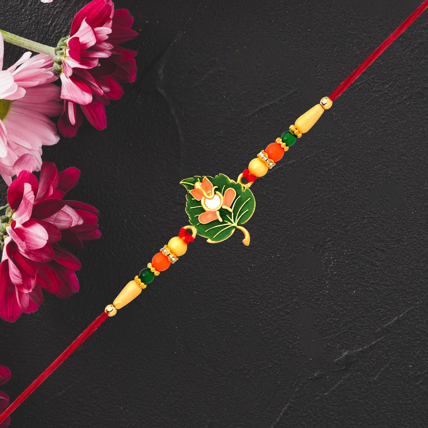 Green Tulsi Leaf Rakhi With Orange Enamel Flower And Beaded Thread Green Tulsi Leaf Rakhi With Orange Enamel Flower And Beaded Thread